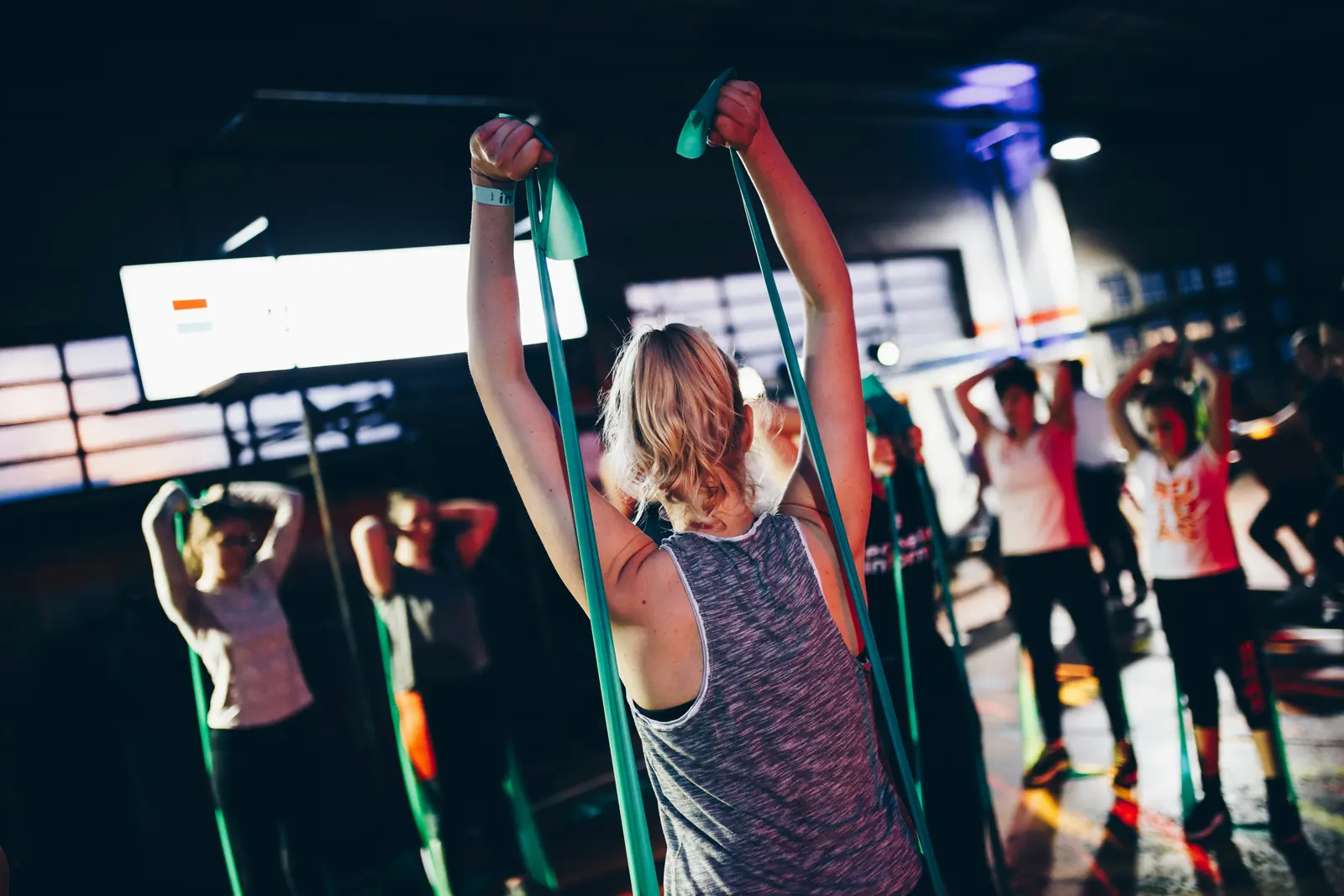 A high-energy group fitness class mid-workout under colored lights