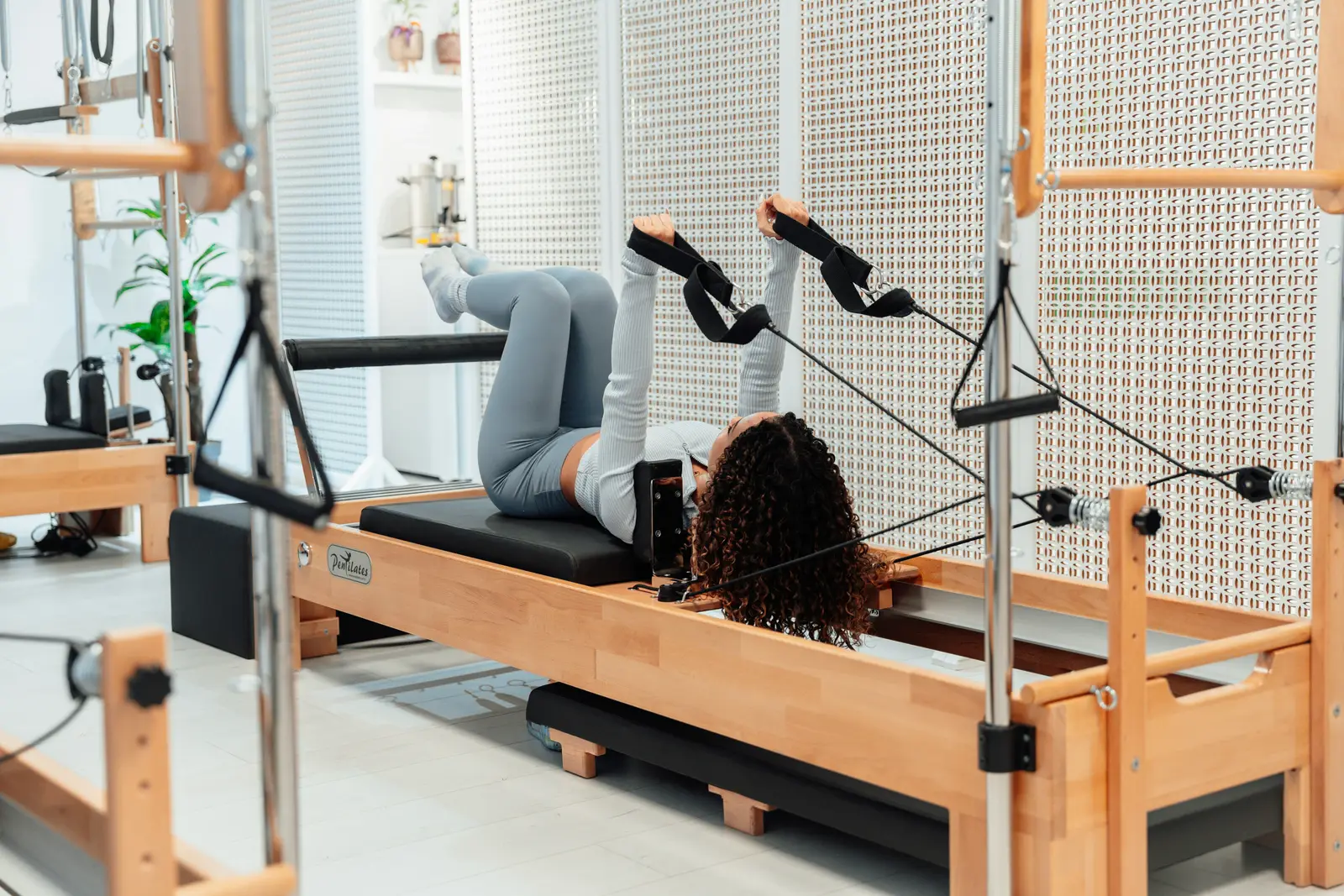 A member on a Pilates reformer in a bright, calm studio