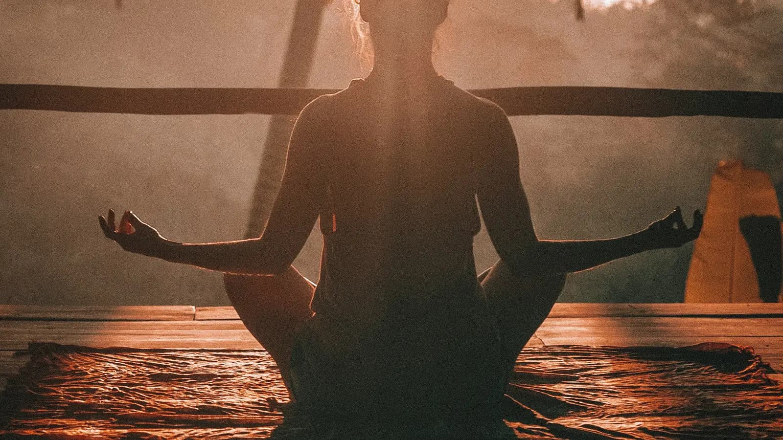 A person meditating in a seated pose at golden sunrise