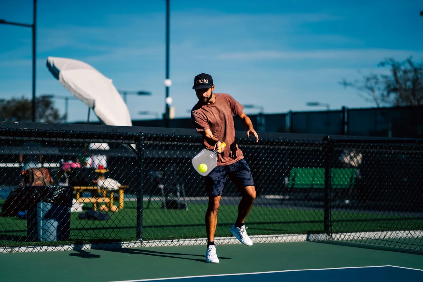 A player mid-swing on an outdoor court under a clear blue sky