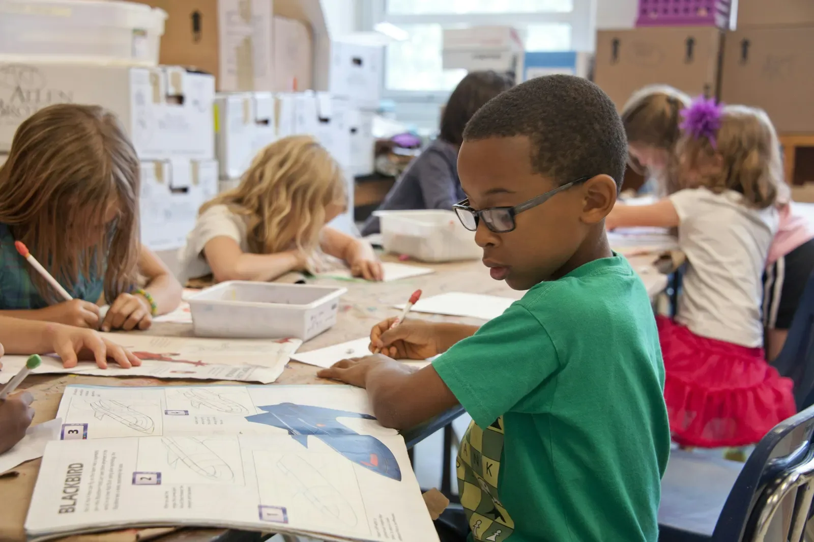 Children drawing and reading together at a bright classroom table
